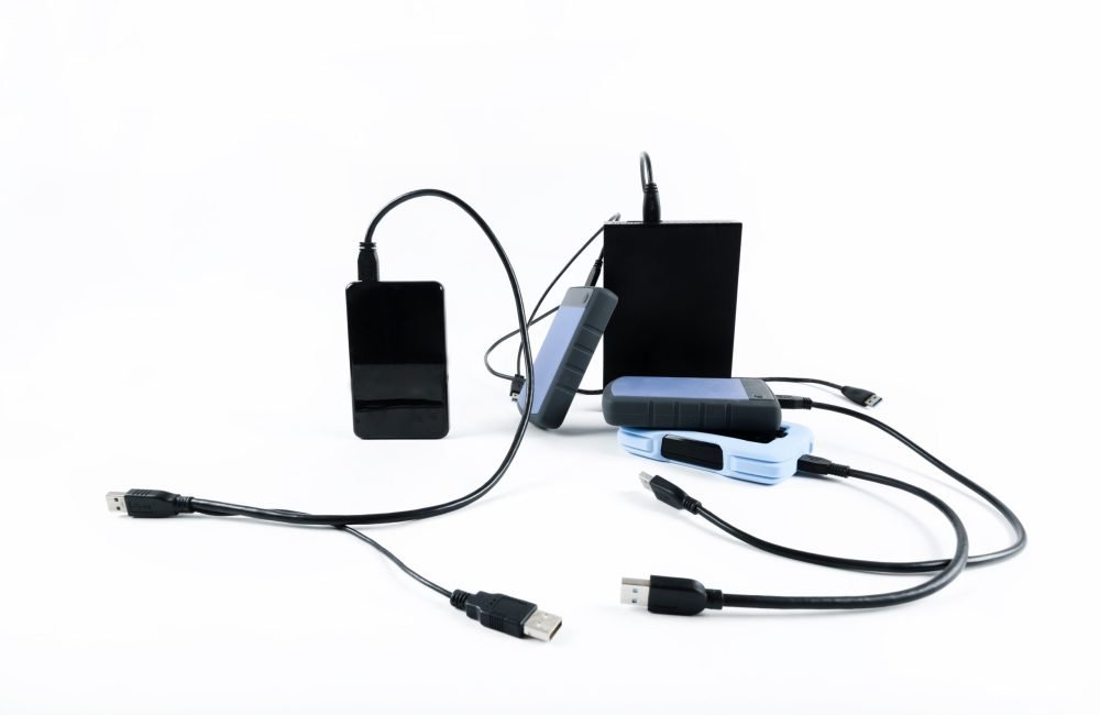 many external hard drives with wires lie on a white background. Hard drives on isolate. many external hard drives with wires lie on a white background. Hard drives on isolate